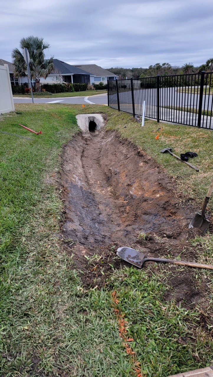 Drainage trench dug along a yard leading to a culvert under the sidewalk